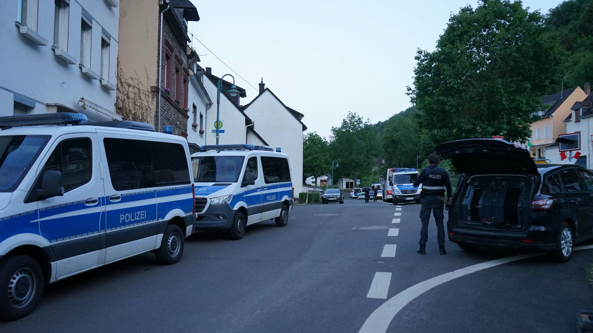 25.05.2024, Rheinland-Pfalz, Kröv: Einsatzfahrzeuge der Polizei stehen im Ortsteil Kövenig. Die Polizei hat nach Hinweisen auf möglicherweise verbotene Musik eine private Feier in dem rheinland-pfälzische Moselort Kröv beendet. Es habe zudem Hinweise darauf gegeben, dass bei der Feier im Landkreis Bernkastel-Wittlich am Samstagabend verfassungsfeindliche Parolen gerufen worden seien, teilte die Polizei am Abend mit. Foto: Wolfgang Steil/Steil-TV/dpa +++ dpa-Bildfunk +++