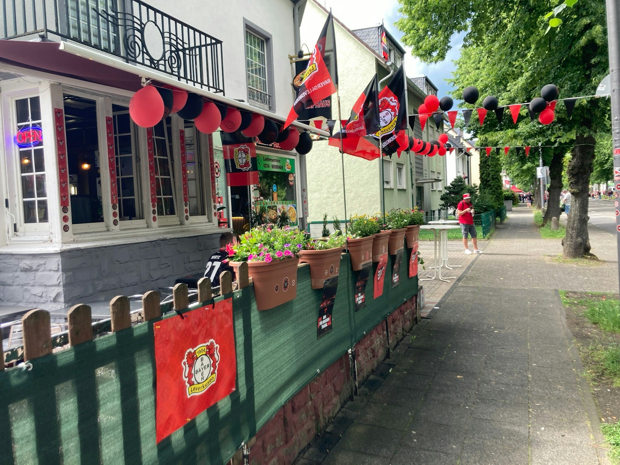 Von Wohnhausfassaden über Restaurants und Lokale bis hin zu Fanartikelständen: Am Straßenrand hat man sich in rot-schwarze Schale geworfen für den Autokorso.