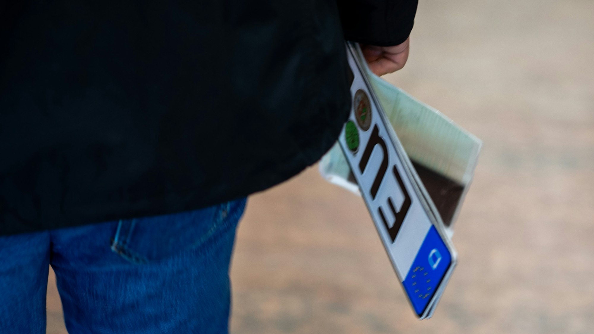 Ein Mann trägt Nummernschild und Papiere in der rechten Hand.