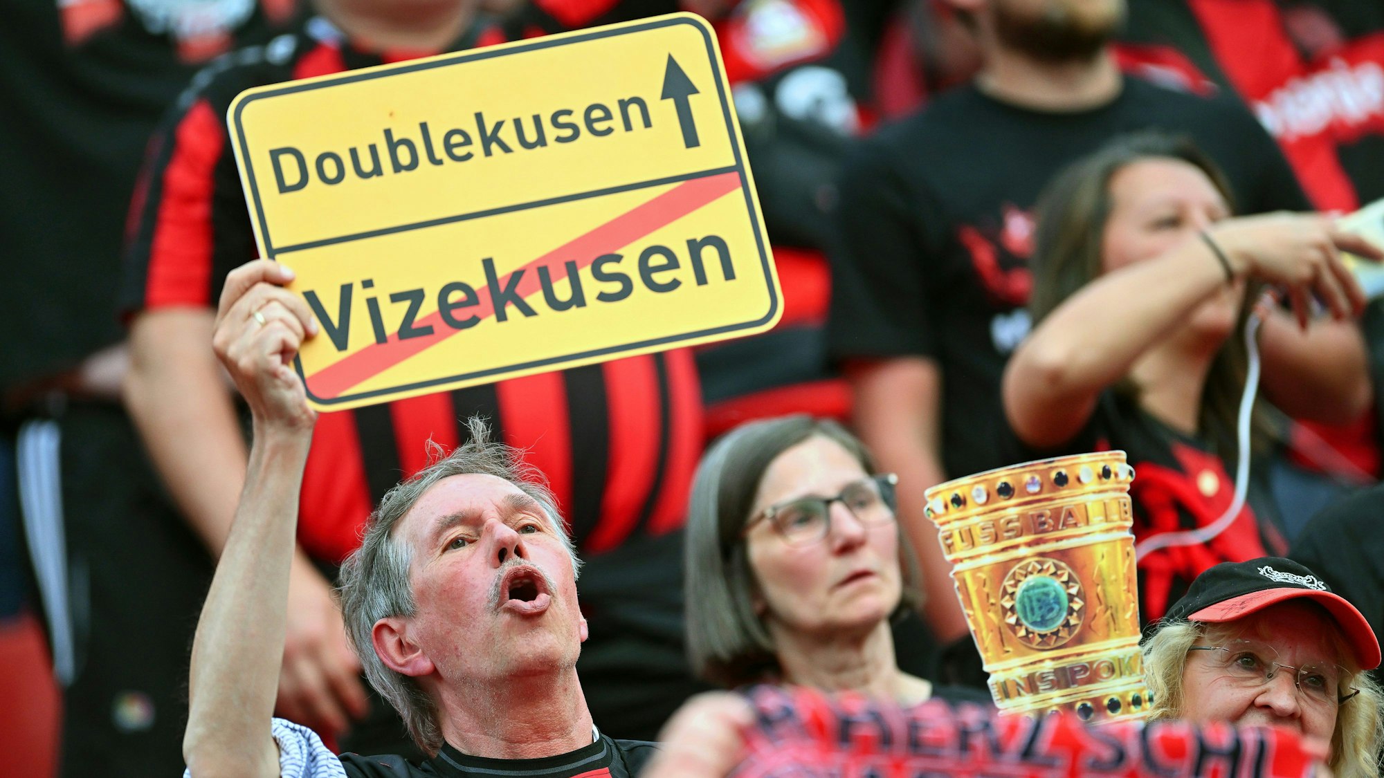 Ein Fan von Leverkusen hält bei der Meisterfeier in der BayArena ein Schild mit der Aufschrift ‚Doublekusen‘ statt ‚Vizekusen‘.