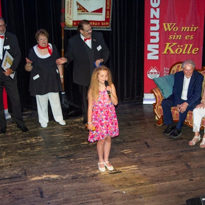 Muuzemändelcher feiern 75 Jahre. In der Mitte steht das jüngste Mitglied Merle, auf dem Sofa sitzen Ludwig Sebus und Renate Baum, daneben steht der Baas, Joachim Badura.