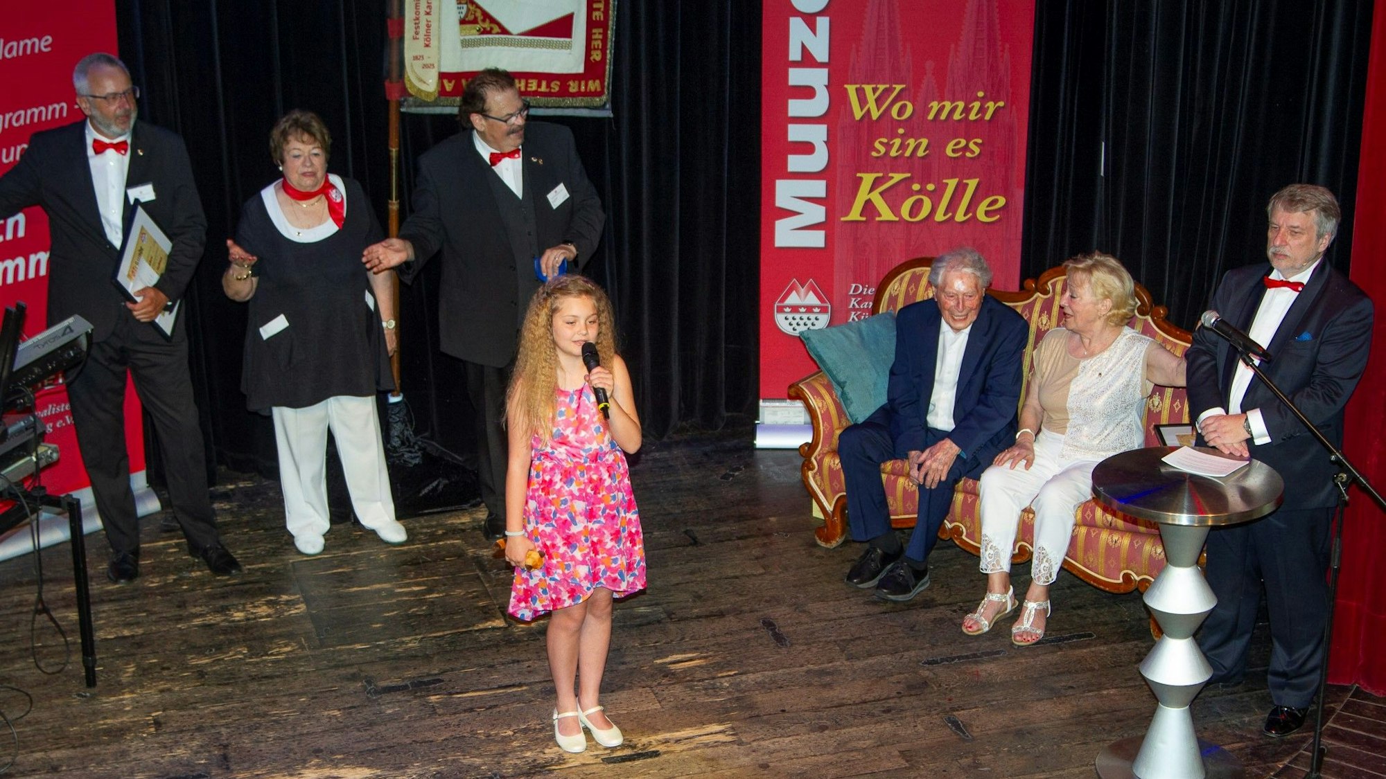 Muuzemändelcher feiern 75 Jahre. In der Mitte steht das jüngste Mitglied Merle, auf dem Sofa sitzen Ludwig Sebus und Renate Baum, daneben steht der Baas, Joachim Badura.