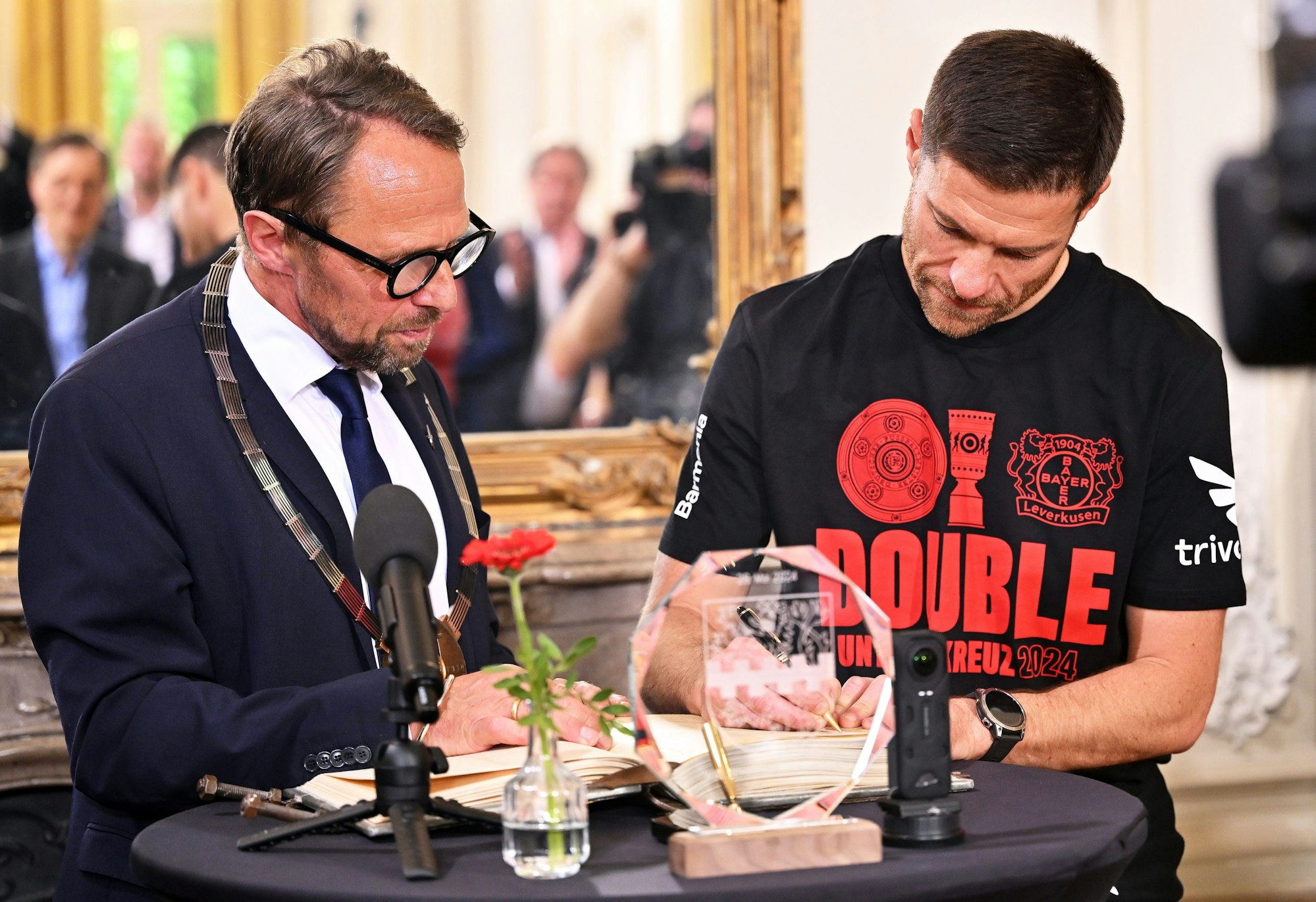 26.05.2024, Nordrhein-Westfalen, Leverkusen: Leverkusens Trainer Xabi Alonso (r) trägt sich bei der Meisterfeier von Bayer Leverkusen im Schloss Morsbroich neben Uwe Richrath (SPD), Oberbürgermeister von Leverkusen, in das Goldene Buch der Stadt ein. Durch den 1:0-Sieg gegen den 1. FC Kaiserslautern hat Bayer Leverkusen den DFB-Pokal gewonnen und damit nach dem Gewinn der deutschen Meisterschaft das Double perfekt gemacht. Foto: Marius Becker/dpa +++ dpa-Bildfunk +++