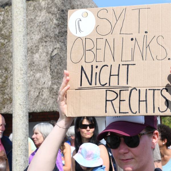 „Sylt oben links. Nicht rechts!“· steht auf einem Plakat, das eine Frau bei einer Mahnwache am Sonntag auf Sylt in der Hand hält. Im Strönwai in Kampen, wo sich auch der Pony-Club befindet, versammelten sich am 26. Mai rund 80 Menschen anlässlich des Rassismus-Eklats um ein Partyvideo auf Sylt zu einer Demo.