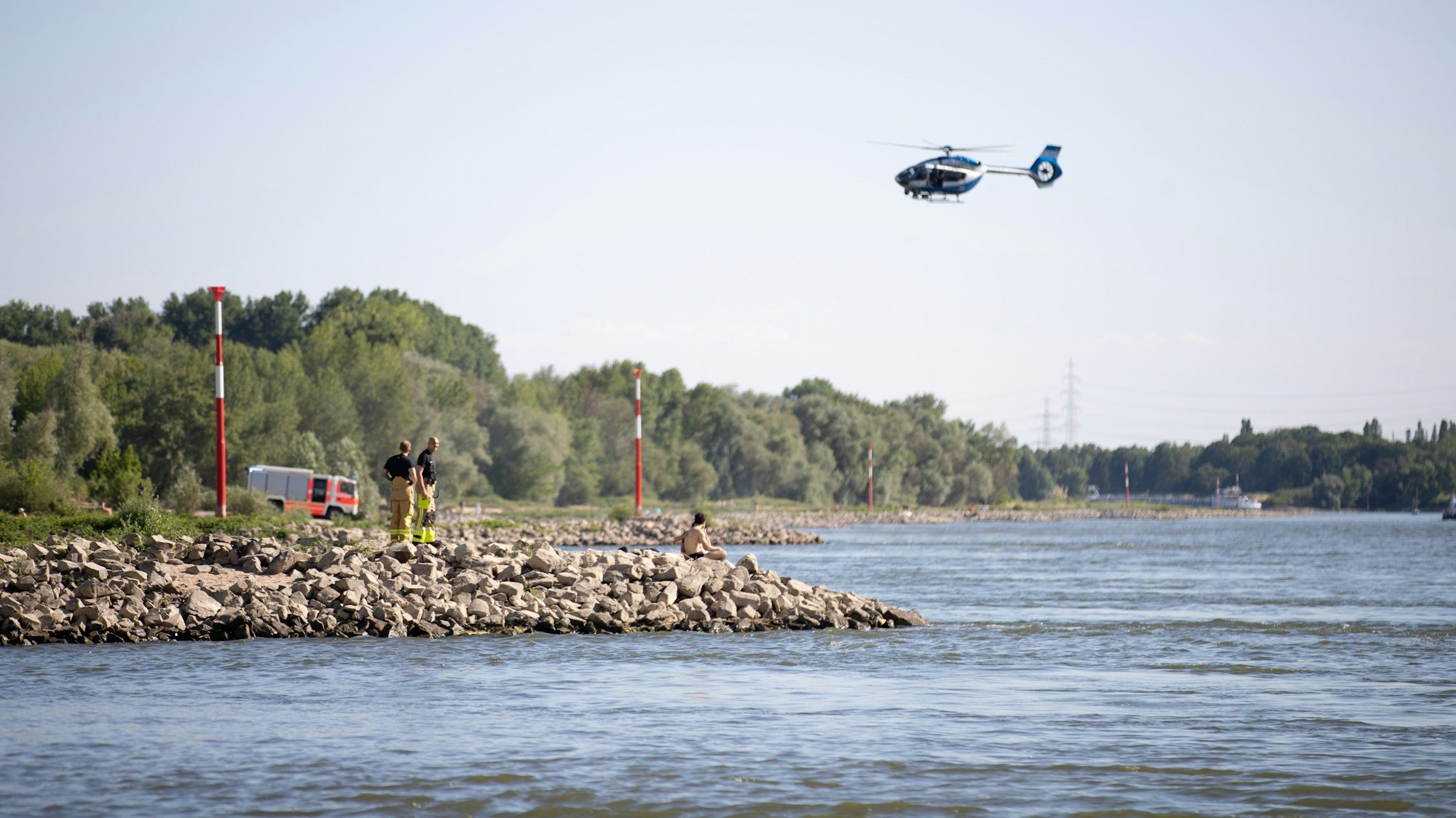 Aus einem Hubschrauber und vom Ufer aus suchen Einsatzkräfte nach einem Schwimmer, der im Rhein von einem Sog erfasst und mitgerissen wurde. (Archivbild)