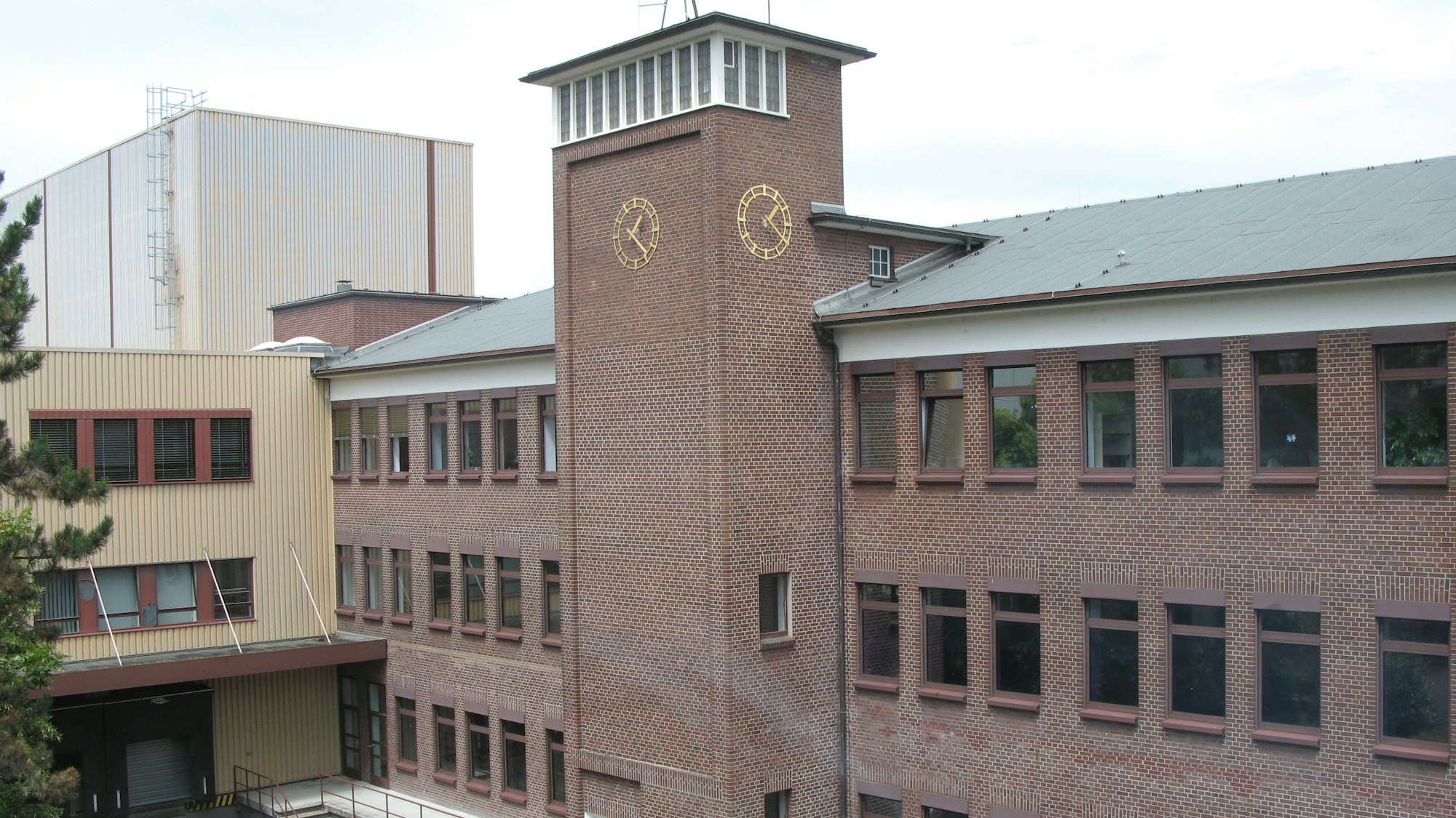 Ein rotes Backsteingebäude mit Turm und Halle.