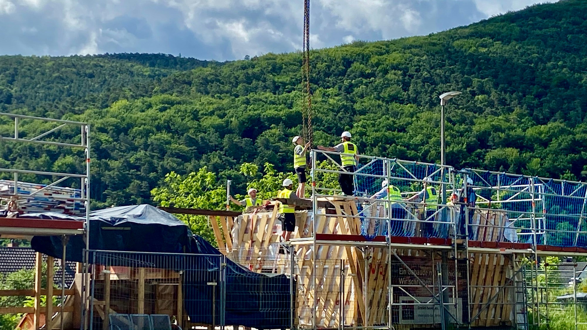 Mitarbeiter in gelben Warnwesten befestigen vier Haken.