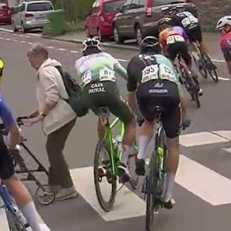 Eine Frau mit Rollator überquerte beim Radrennen „Rund um Köln“ bei der Durchfahrt in Wipperfürth die Straße.