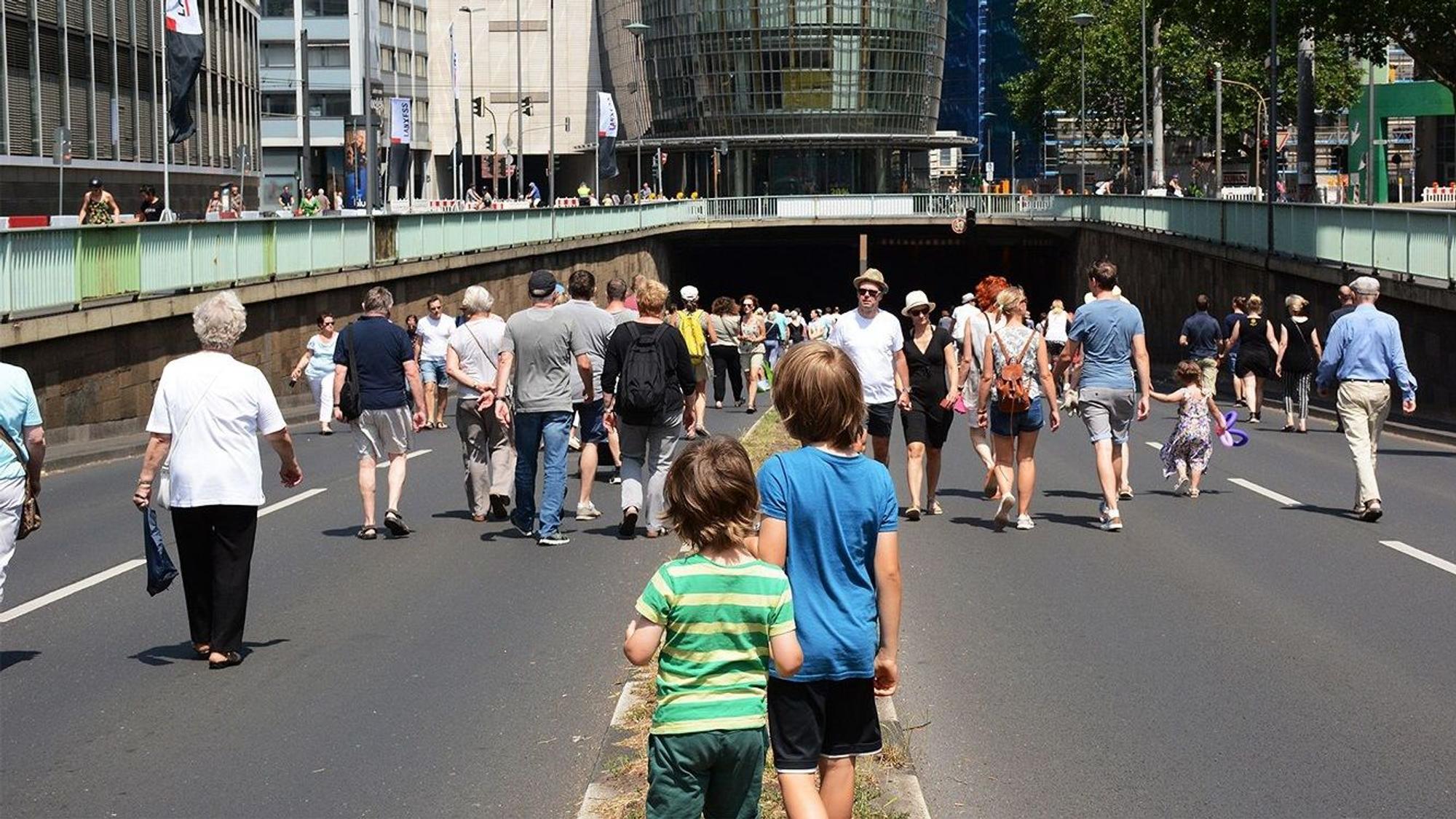 Zu sehen sind Menschen, die über eine autofreie Nord-Süd-Fahrt in Köln laufen.