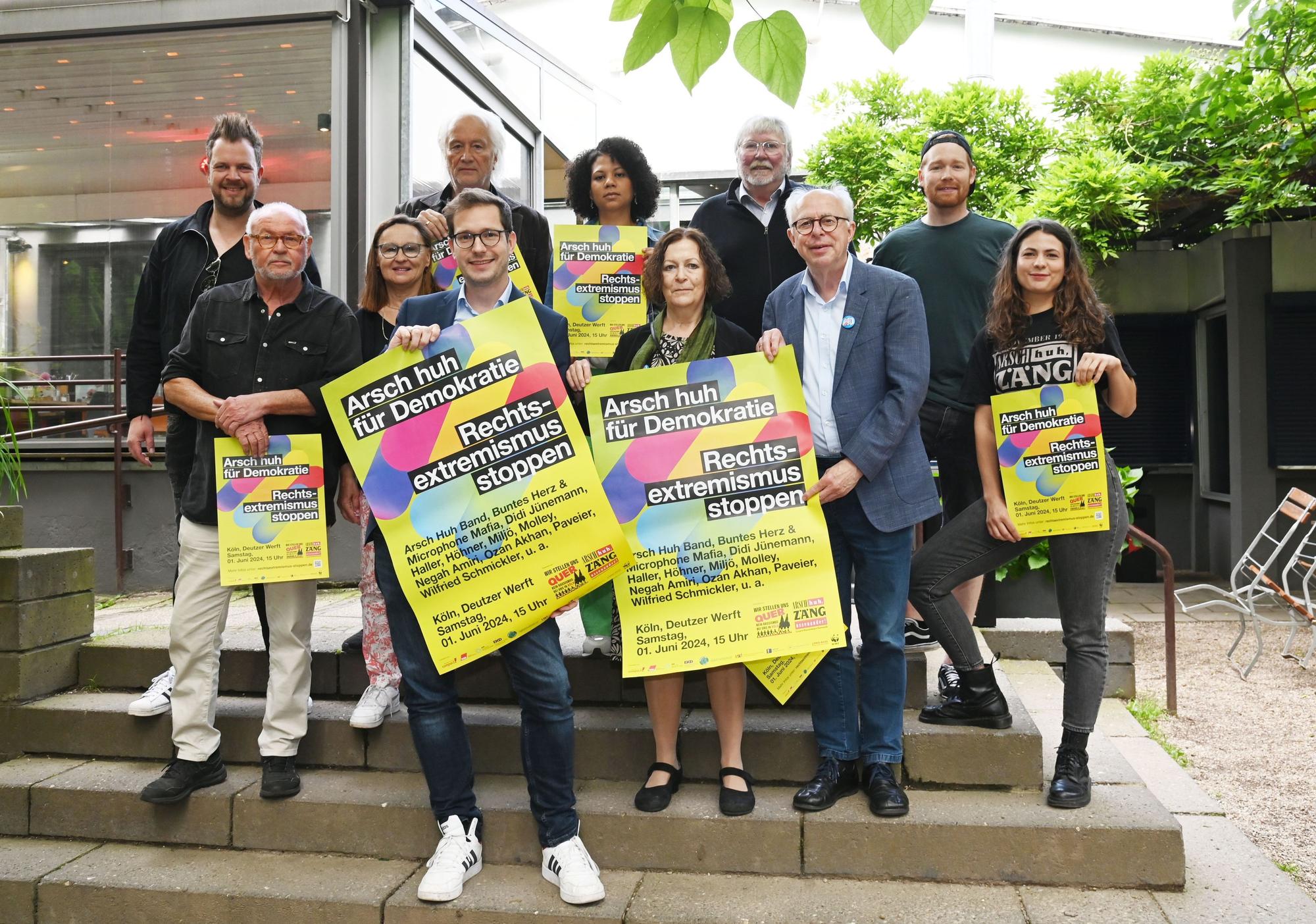 Künstler und Veranstaltende von „Arsch huh für die Demokratie“ zeigen Plakate für die Kundgebung am 1. Juni 2024