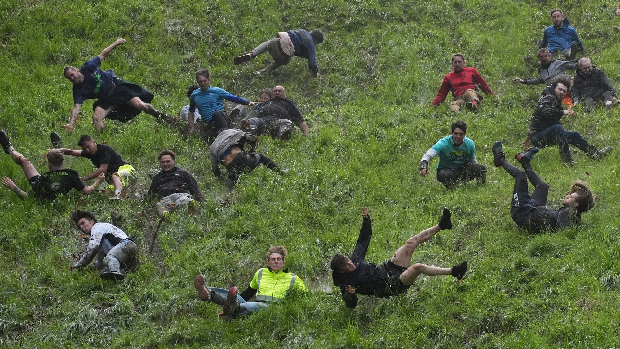 27.05.2024, Großbritannien, Brockworth: Tom Kopke aus Deutschland (M, neongelbes Shirt) wirft sich mit anderen Teilnehmern beim jährlichen Käserennen "Cheese-Rolling" bei Cooper's Hill in Brockworth, Gloucestershire einen Abhang hinunter. Er gewann das erste Rennen. (zu dpa Käserennen in England: Mann aus München gewinnt kuriosen Wettbewerb) Foto: Jacob King/PA Wire/dpa +++ dpa-Bildfunk +++