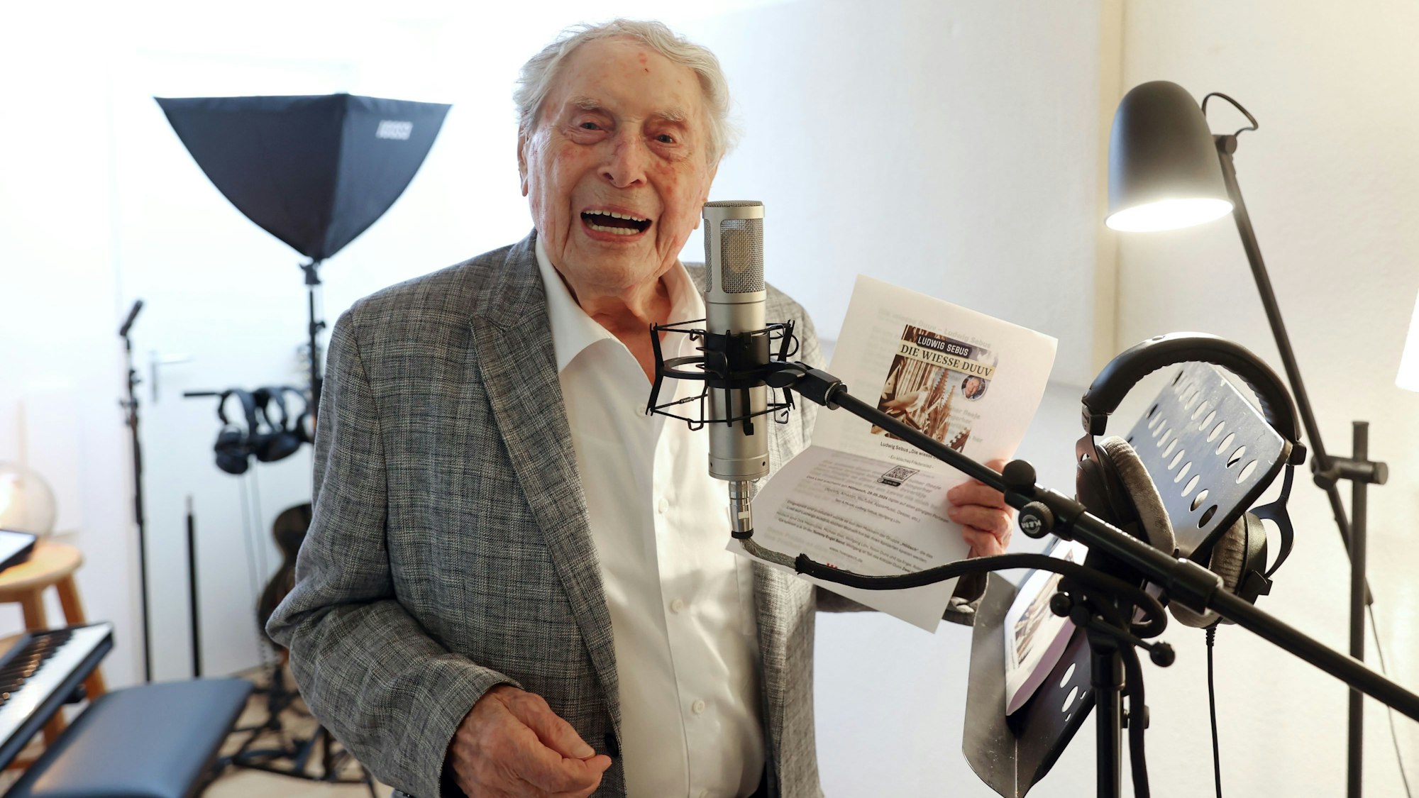 Ludwig Sebus steht lächelnd in einem Studio hinter einem Mikrofon.