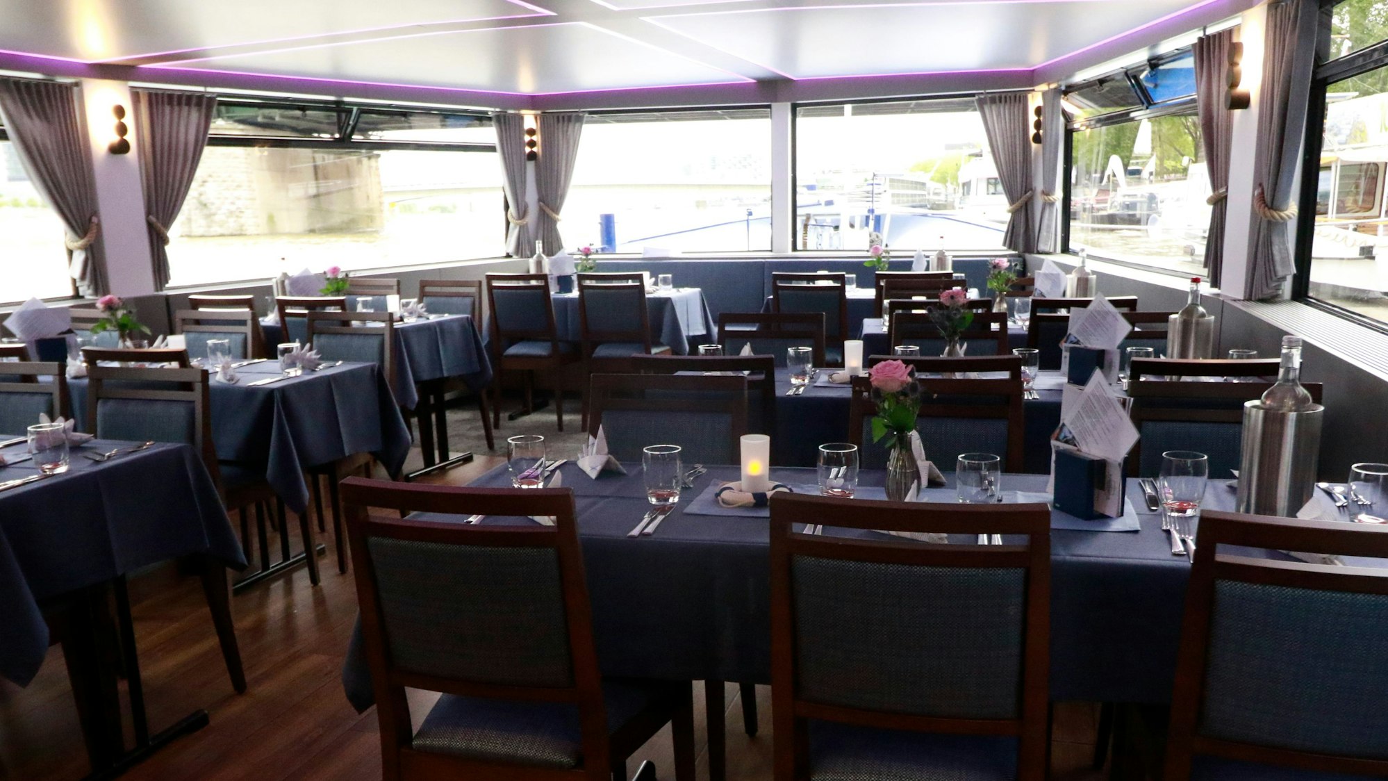 Zu sehen ist der Innenbereich eines Schiffes mit Tischen und Stühlen.