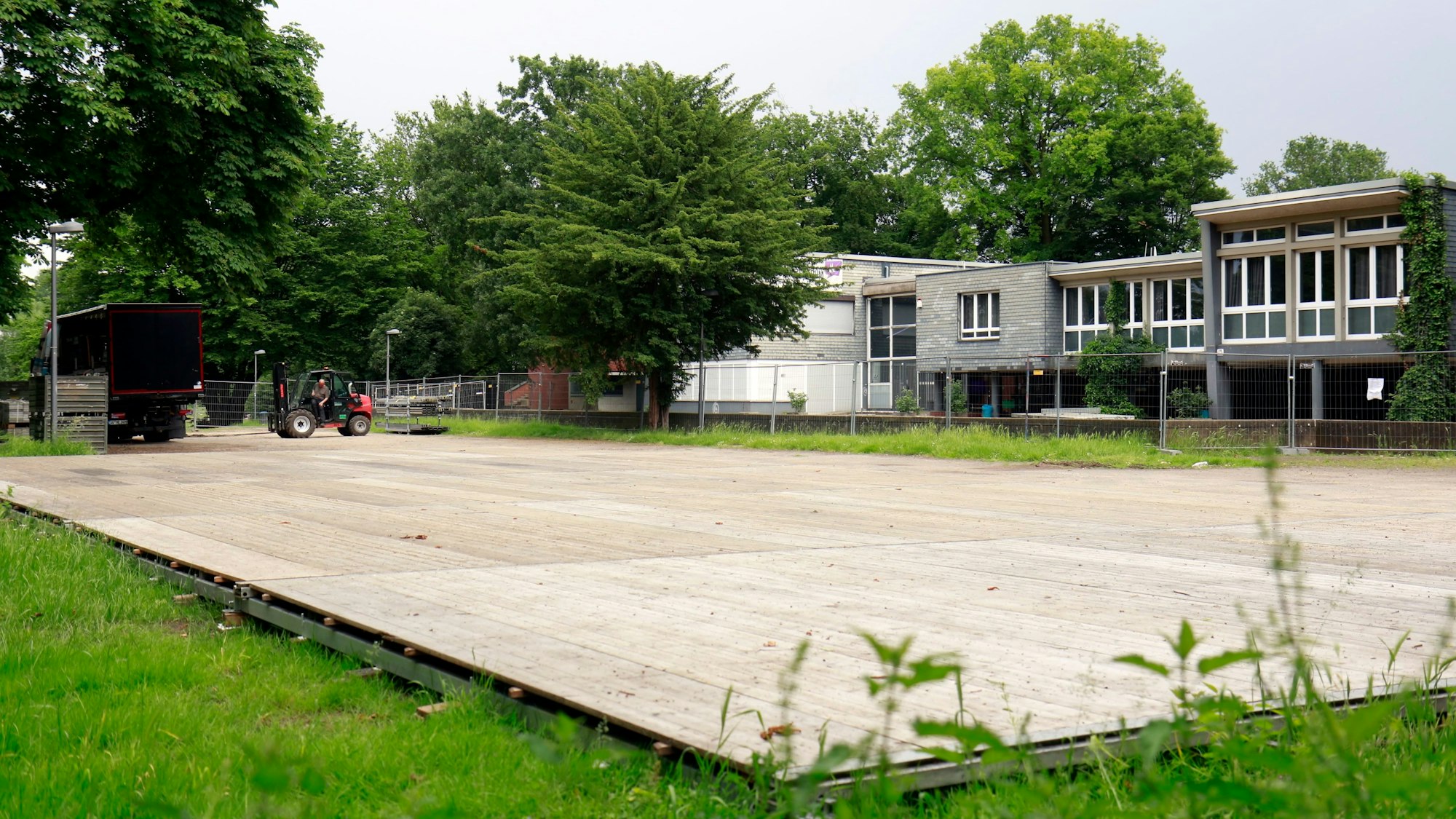 Ein großer Zeltboden aus Holzpaneelen auf der Wiese im Jugendpark in Köln.