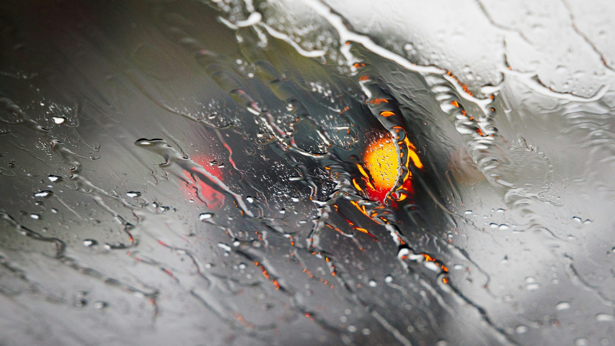 Nordrhein-Westfalen, Bielefeld: Ein blinkendes Fahrzeug ist hinter einer regennassen Windschutzscheibe eines Autos zu sehen. (Symbolbild)