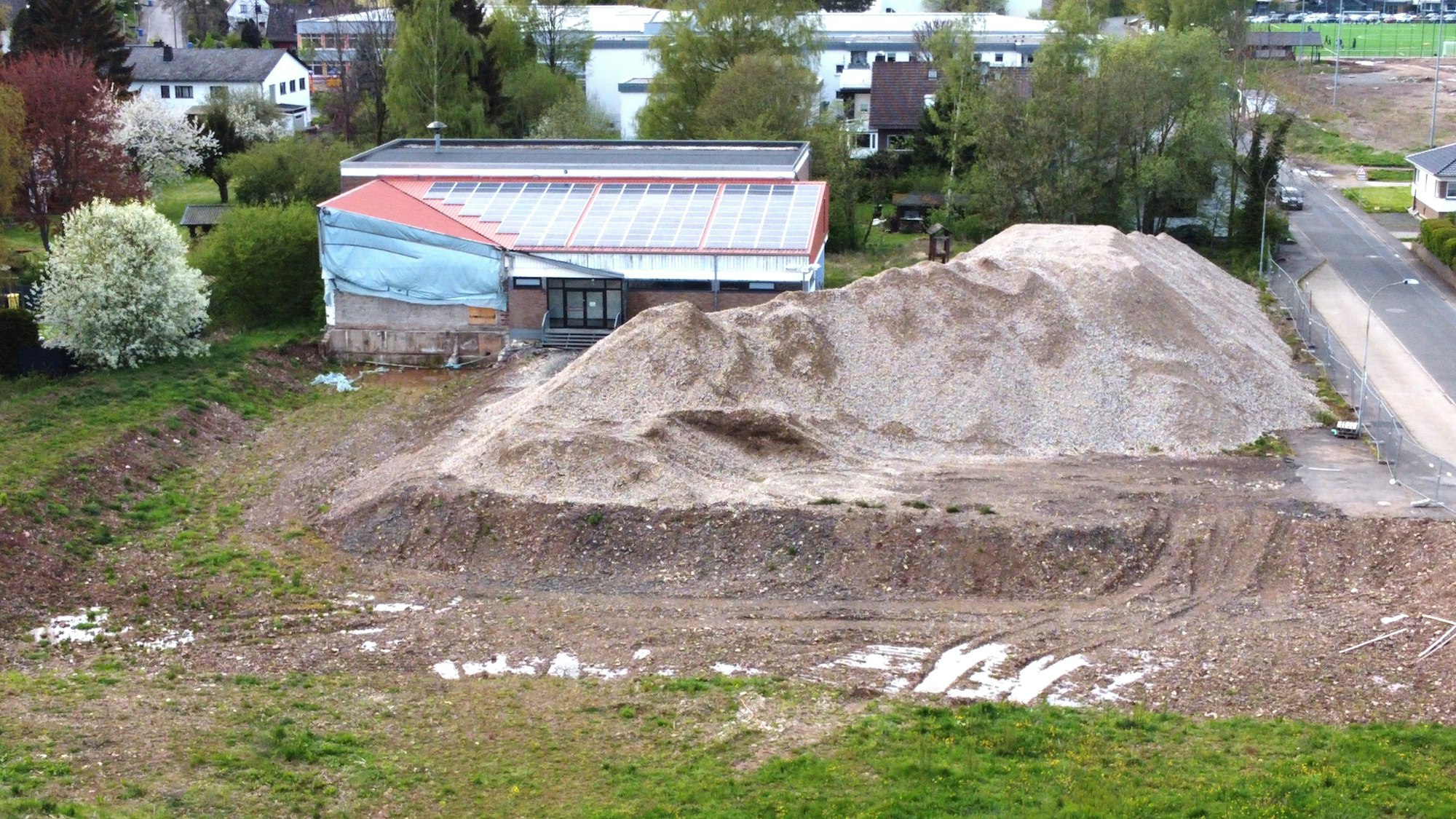 Blick auf die alte Turnhalle, neben der ein großer Schutthaufen liegt.