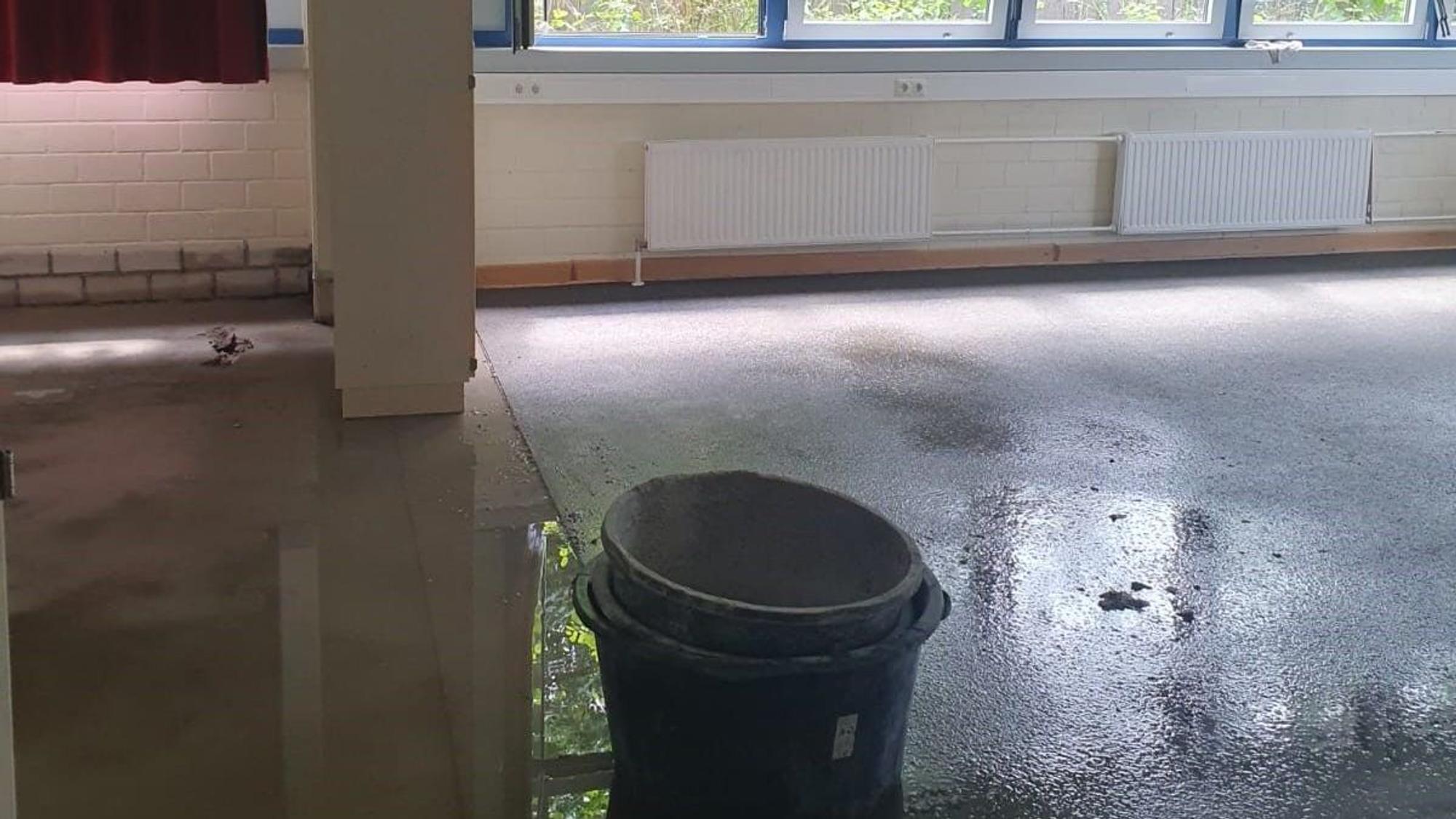Ineinander gestapelte Eimer stehen auf dem noch nassen Boden.