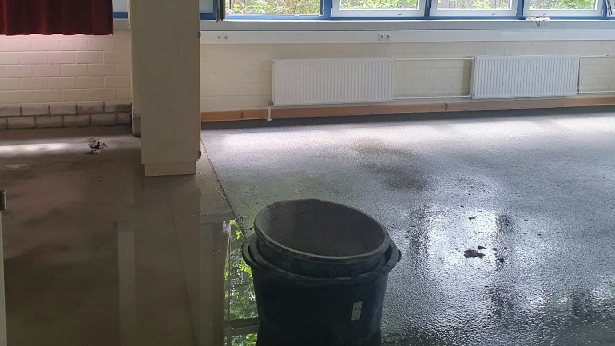 Ineinander gestapelte Eimer stehen auf dem noch nassen Boden.