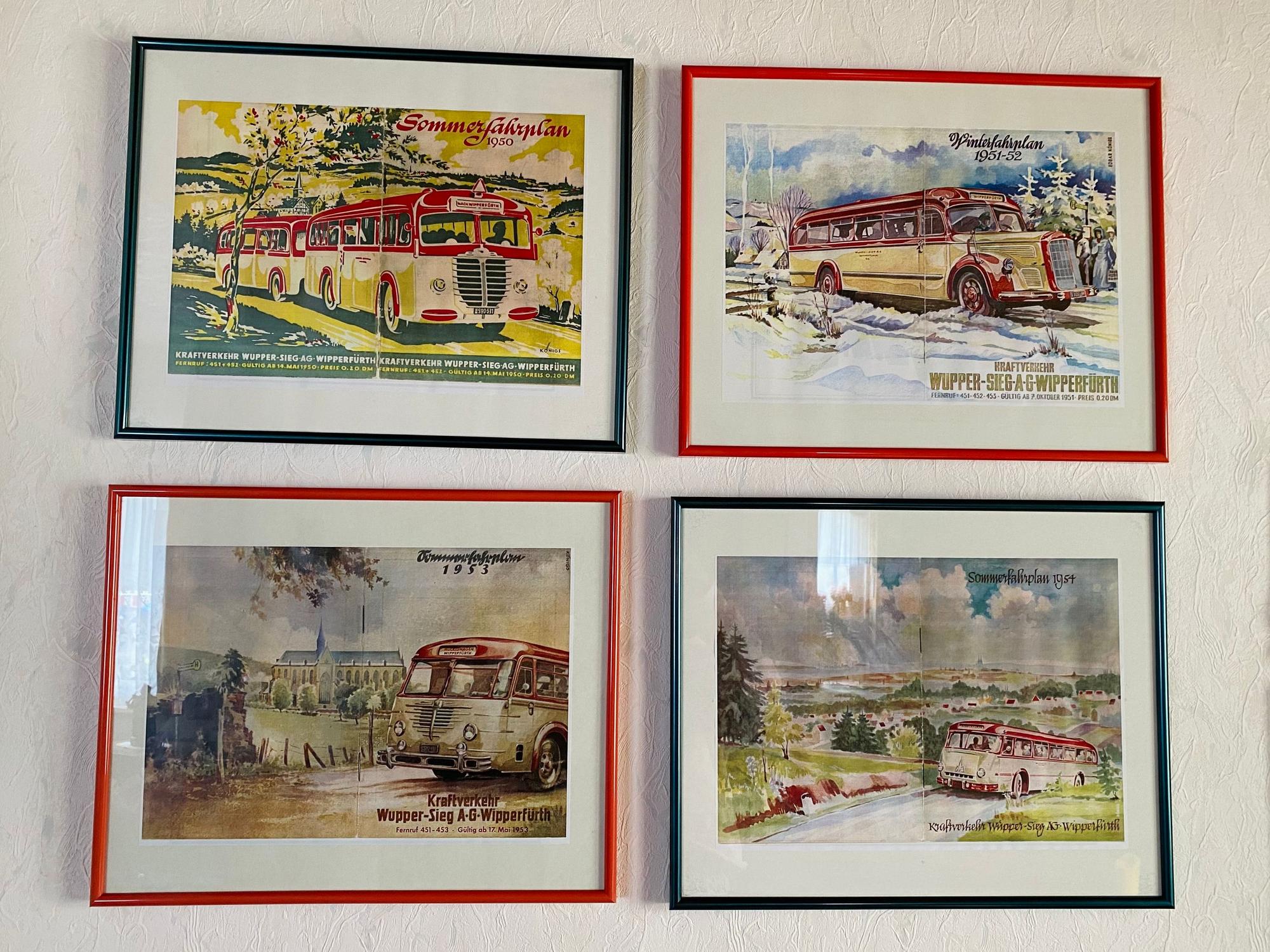 Vier Bilderrahmen mit Zeichnungen von Bussen hängen an einer Wand.