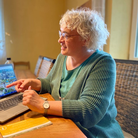 Barbara Lehmann-Detscher, Co-Vorsitzende des Vereins Weilerswist Zero, präsentiert ein KI-generiertes Bild auf ihrem Laptop.