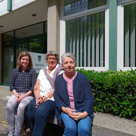 Helga Coen und Margret Eimermacher aus dem Seniorenbeirat sitzen mit Schriftführerin Jenny Zyball vor dem Burscheider Rathaus.
