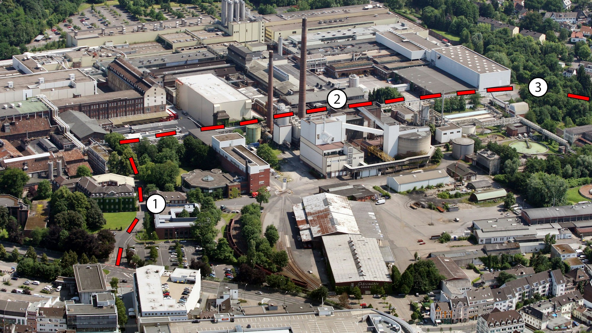 das Zanders-Areal aus der Vogelperspektive von einem Flugzeug aus gesehen. Eingezeichnet ist die am 25. Mai 2024 freigegebene Straße über das Gelände.