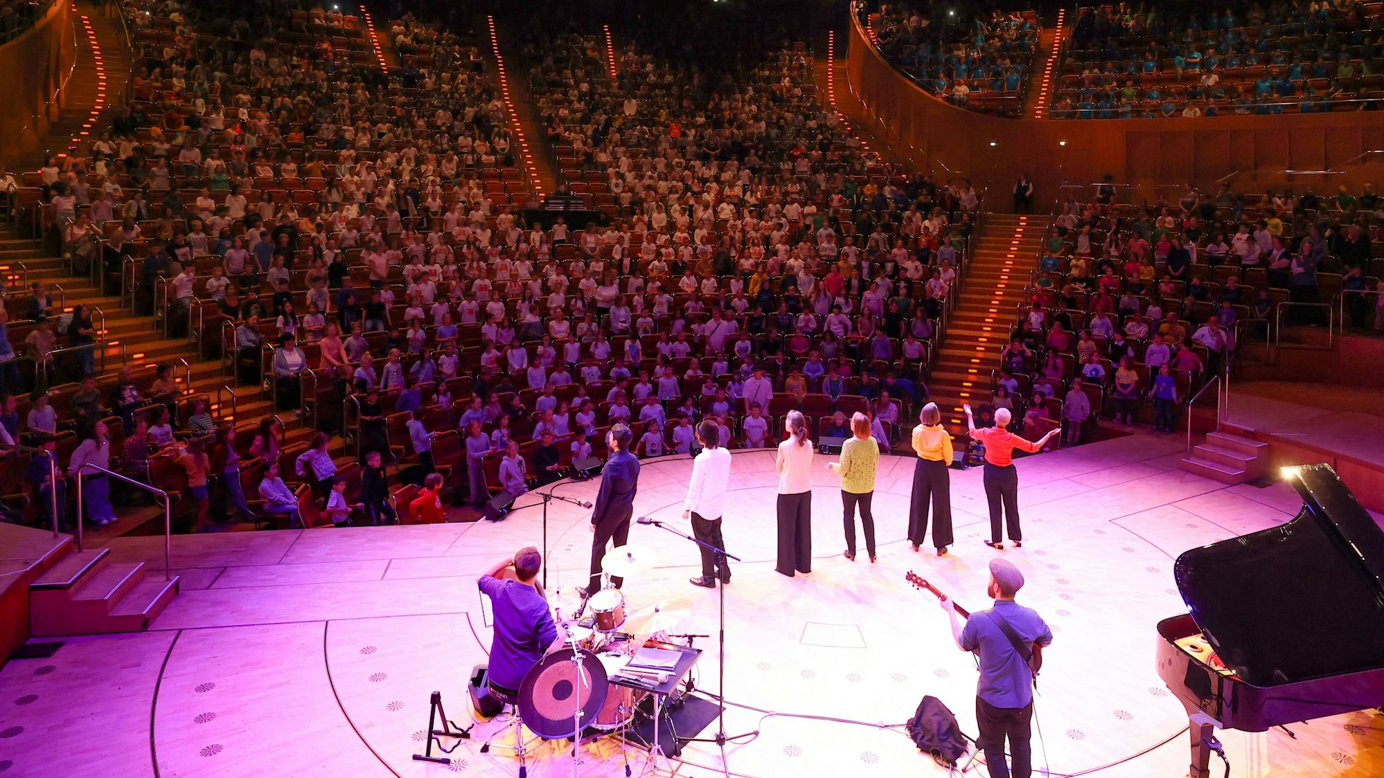 Fast alle Reihen der Kölner Philharmonie sind mit 1.300 Grundschülern besetzt, die von einer Band begleitet ein Konzert geben.