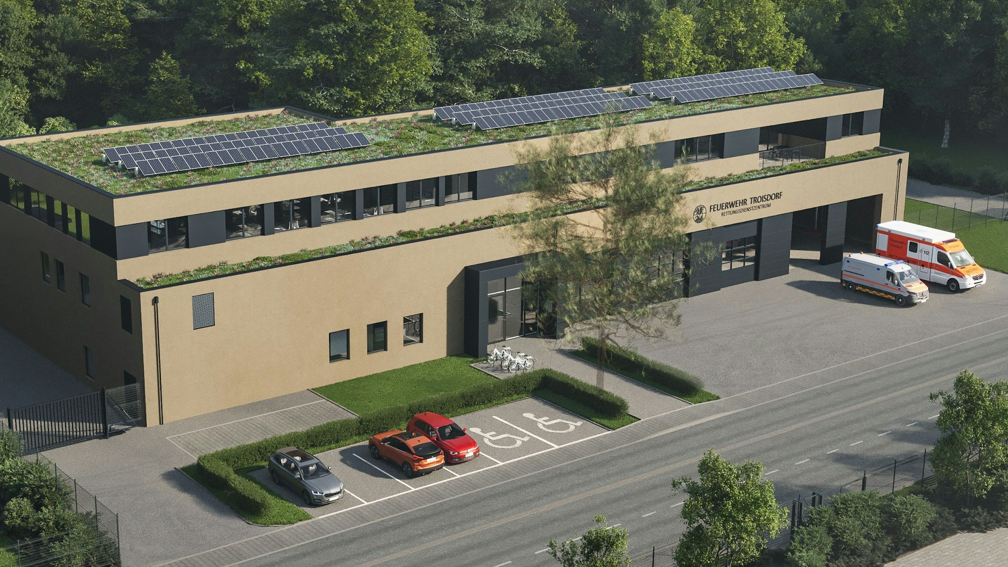 Ein flaches Gebäude mit Dachbegrünung und Photovoltaikanlage auf dem Dach. Vor der Fahrzeughalle sind Einsatzfahrzeuge des Rettungsdienstes abgestellt.