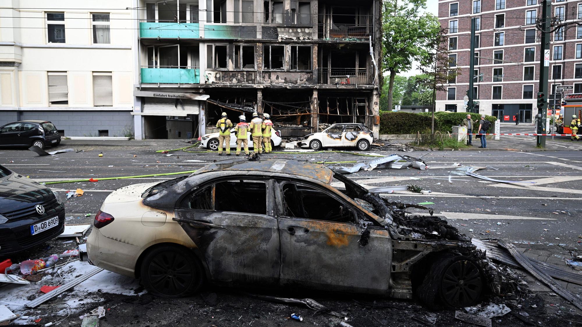 Feuerwehrleute stehen vor einem Wohnhaus, in dem ein Brand wütete.