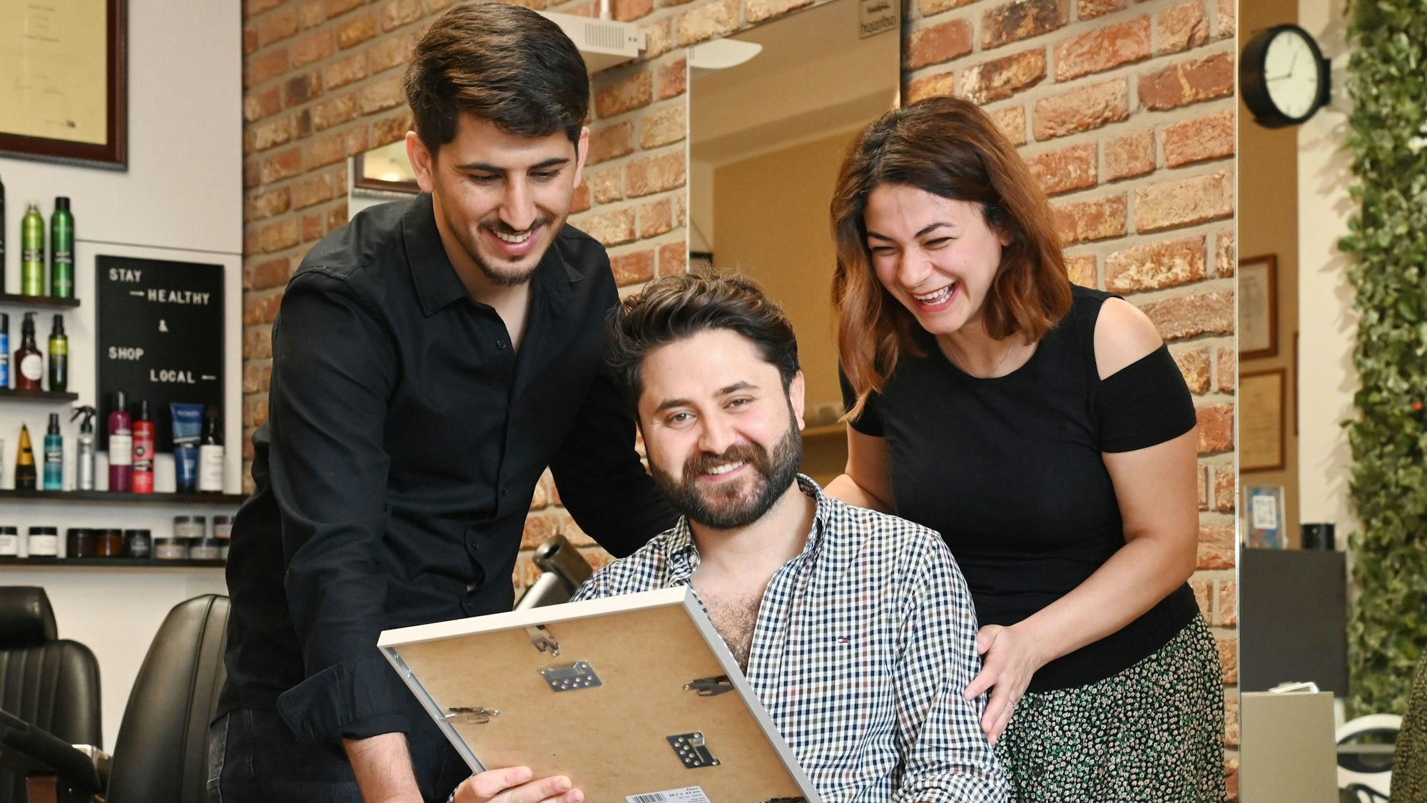 Drei Menschen freuen sich über einen Preis.