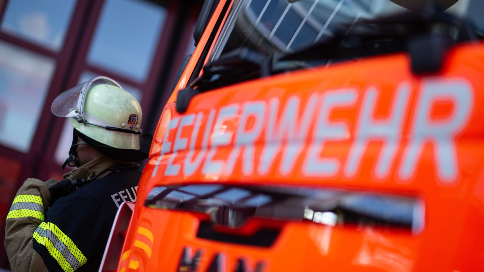 Eine Einsatzkraft der Feuerwehr steht neben einem Einsatzfahrzeug der Feuerwehr (Symbolfoto).