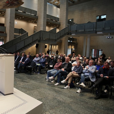 Zu sehen ist Robert Voigtsberger (Beigeordneter für Bildung, Sport der Stadt Köln), der zu Publikum spricht.
