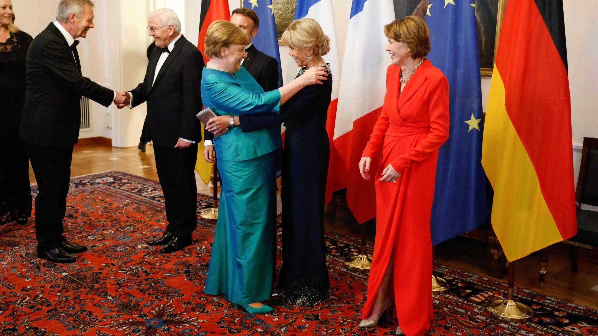 Brigitte Macron und Angela Merkel begrüßen sich herzlich mit einer Umarmung.