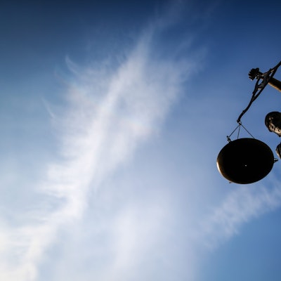 Eine Justitia vor einem Gerichtsgebäude, fotografiert gegen den blauen Himmel.