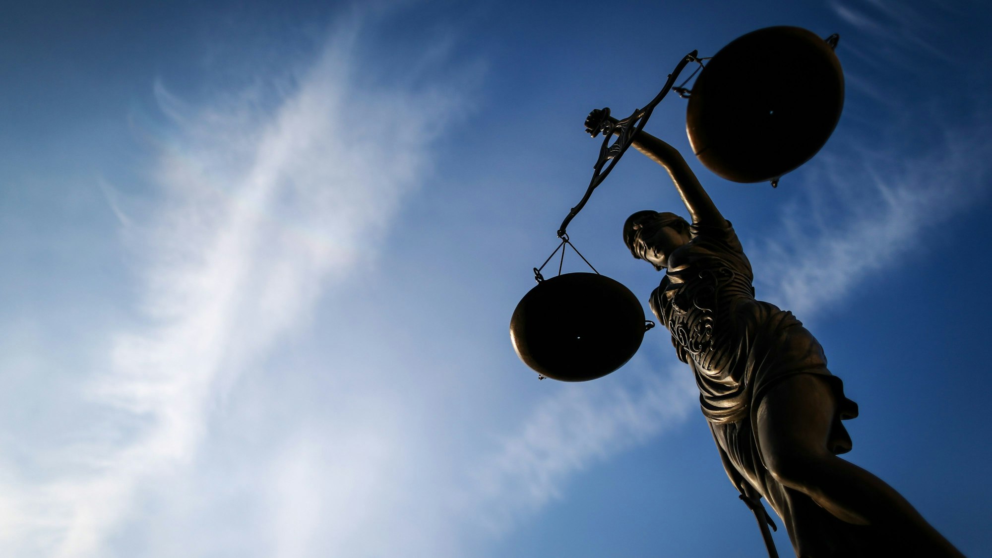 Eine Justitia-Statur unter einem Himmel mit ein paar Wolken aus der Froschperspektive (Archivbild)