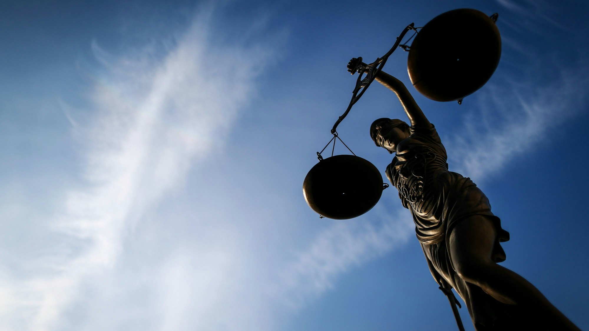 Eine Justitia vor einem Gerichtsgebäude, fotografiert gegen den blauen Himmel.