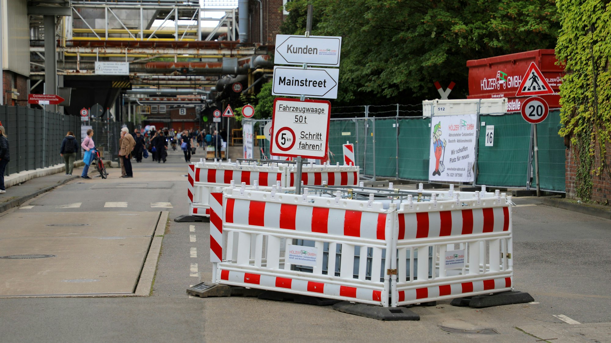 Baken teilen eine Straße auf dem Zanders-Gelände in Bergisch Gladbach in zwei Spuren. Auf Wegweisern steht „Kunden“ und „Mainstreet“.