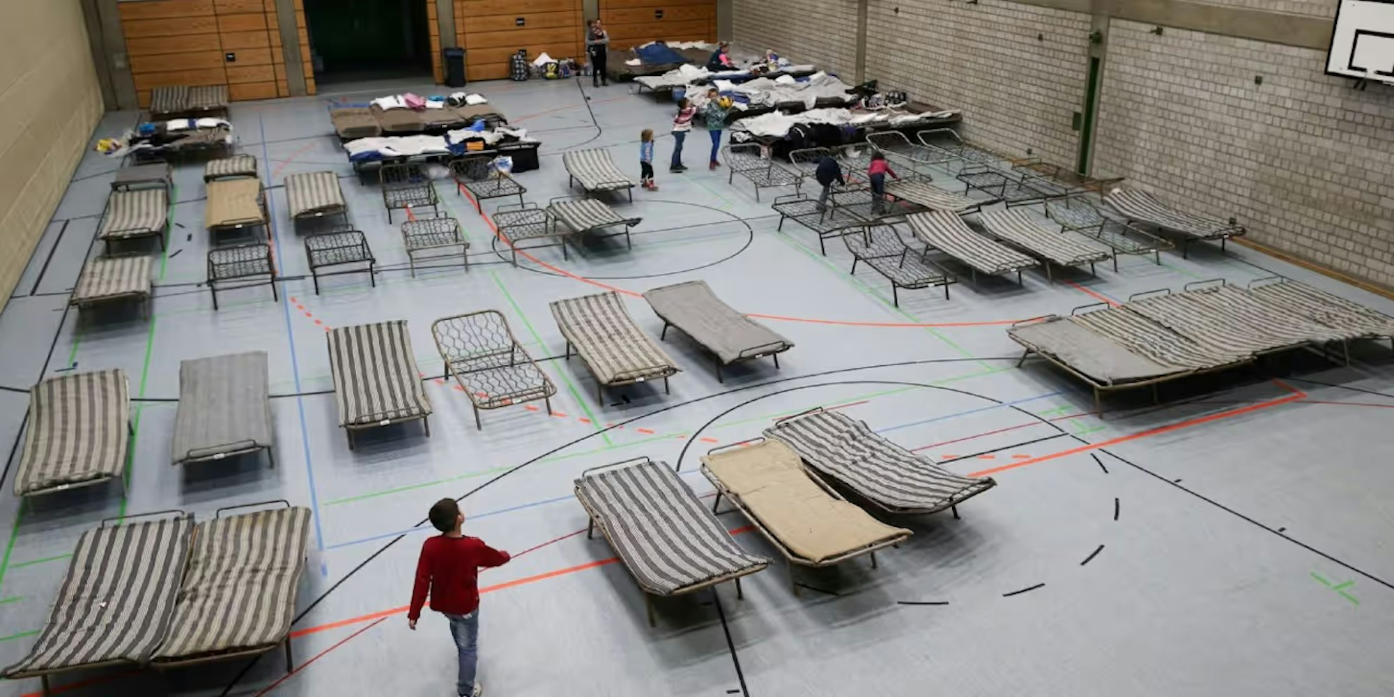 Auf dem Foto ist eine Sporthalle mit Feldbetten zu sehen.