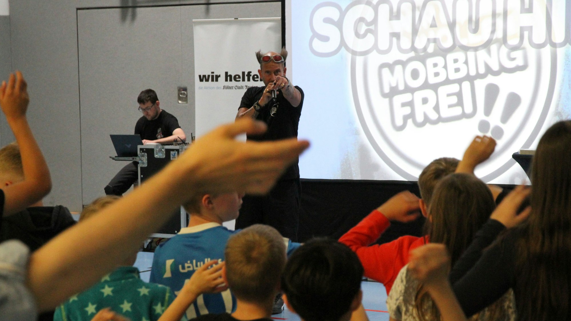 Ein Mann mit Mikrofon vor einer Gruppe von Grundschülern