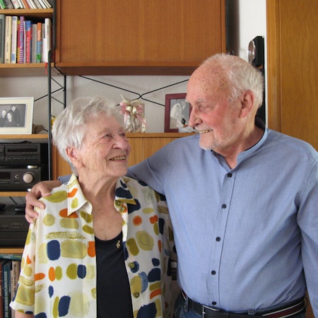 Ein grauhaariger Mann und eine grauhaarige Frau sehen sich tief in die Augen.