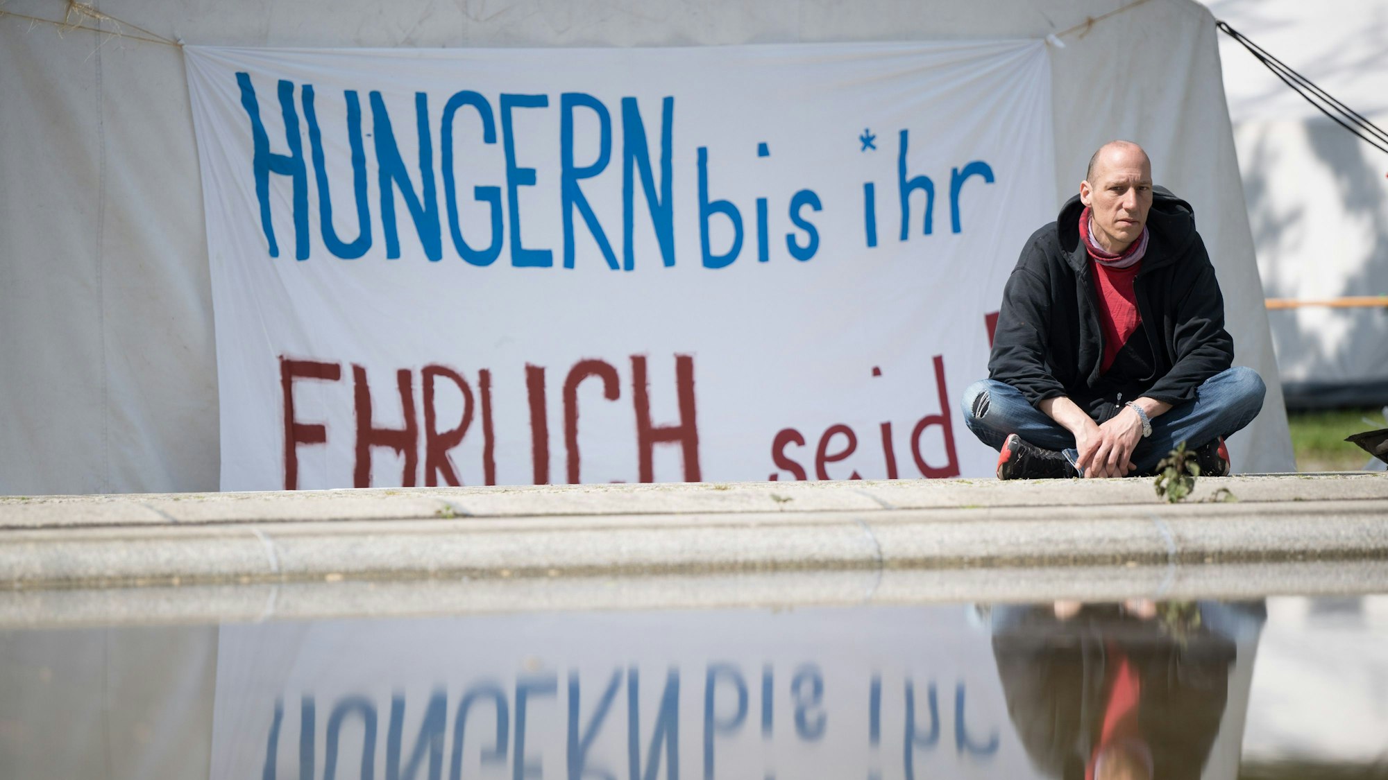 ARCHIV - 29.04.2024, NA, Berlin: Wolfgang Metzeler-Kick sitzt am neuen Standort des Hungerstreik-Camps des Bündnisses «Hungern bis ihr ehrlich seid» im Regierungsviertel vor einem Banner. (zu dpa: «Klima-Hungerstreik: Ein Teilnehmer laut Kampagne in Lebensgefahr») Foto: Sebastian Gollnow/dpa +++ dpa-Bildfunk +++