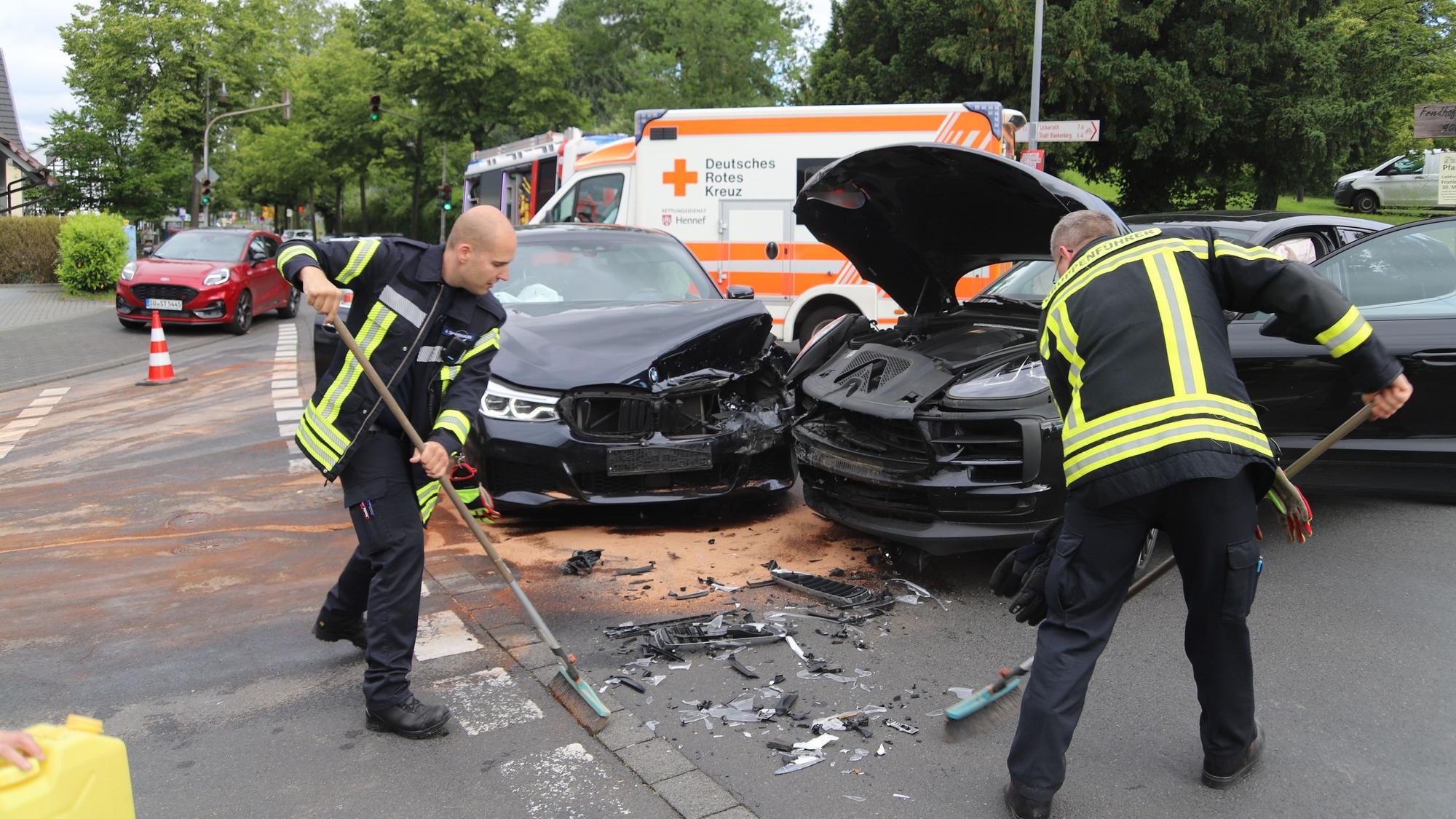 Beim Abbiegen von der Frankfurter in die Hanftalstraße in Hennef hat eine Porschefahrerin die Vorfahrt eines Mercedesfahrers übersehen. Feuerwehrleute reinigen die Fahrbahn.
