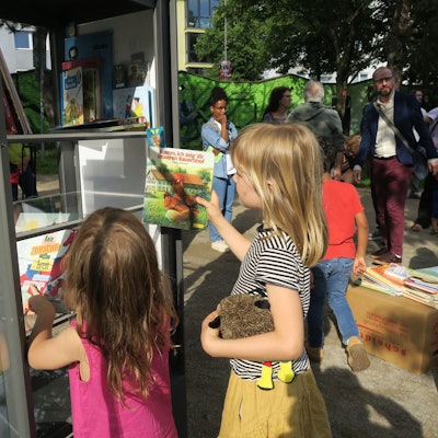 Kinder beim Lesen, Einsortieren der Bücher in den neuen Bücherschrank im Leo-Amann-Park.
