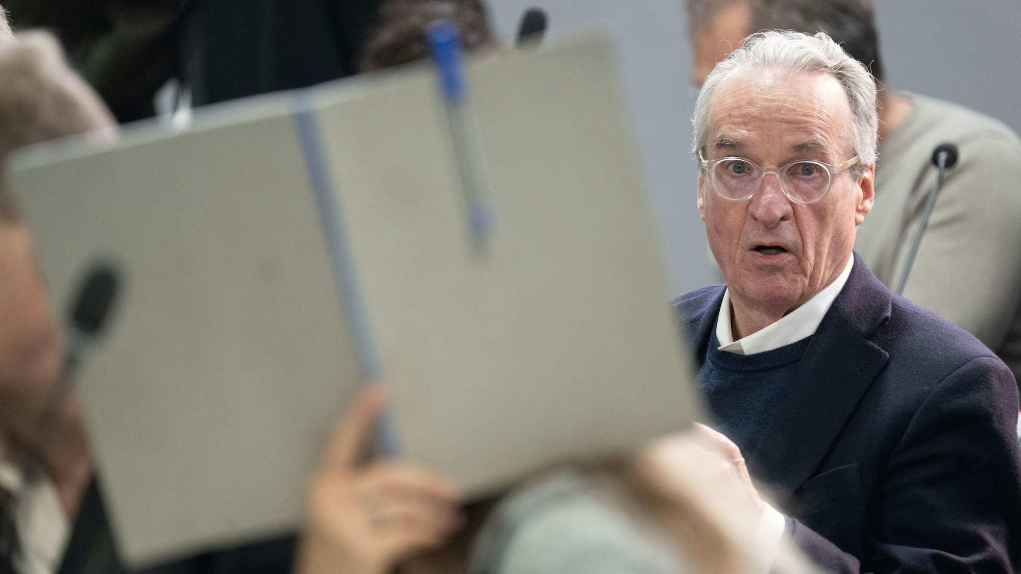 dpatopbilder - 28.05.2024, Hessen, Frankfurt/Main: Der Hauptangeklagte Heinrich XIII. Prinz Reuß sitzt bei der Fortsetzung des Prozesses gegen eine mutmaßliche ·Reichsbürger-Gruppe· um um Prinz Reuß auf der Anklagebank hinter einer Mitangeklagten, die ihr Gesicht mit einer Mappe verdeckt. Die Bundesanwaltschaft legt den insgesamt neun Angeklagten unter anderem die Mitgliedschaft in einer terroristischen Vereinigung zur Last. Foto: Boris Roessler/dpa-POOL/dpa +++ dpa-Bildfunk +++