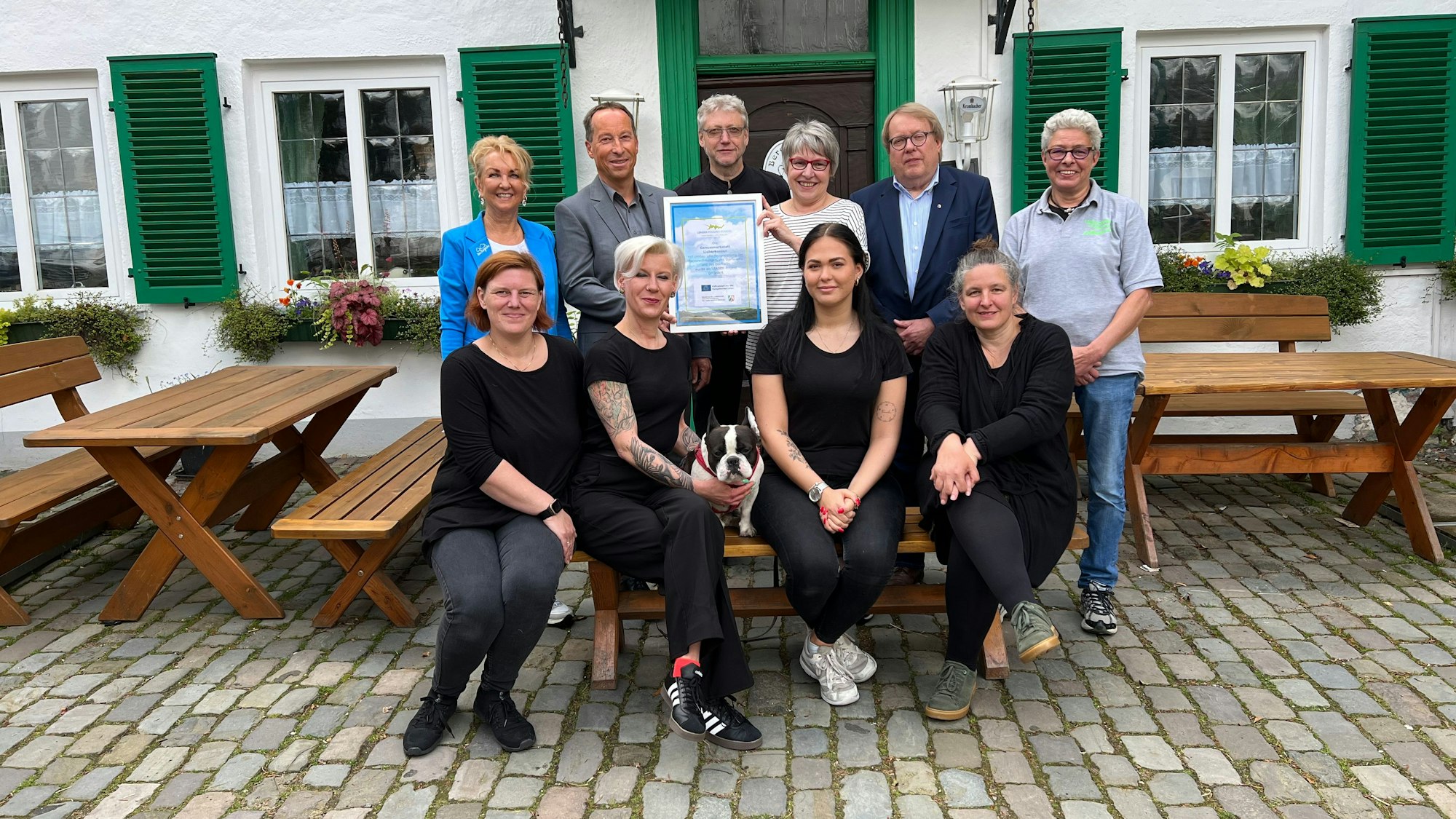 Vor dem neuen Gasthof sitzen und stehen die Familie sowie Vertreter von Leader und aus der Politik.