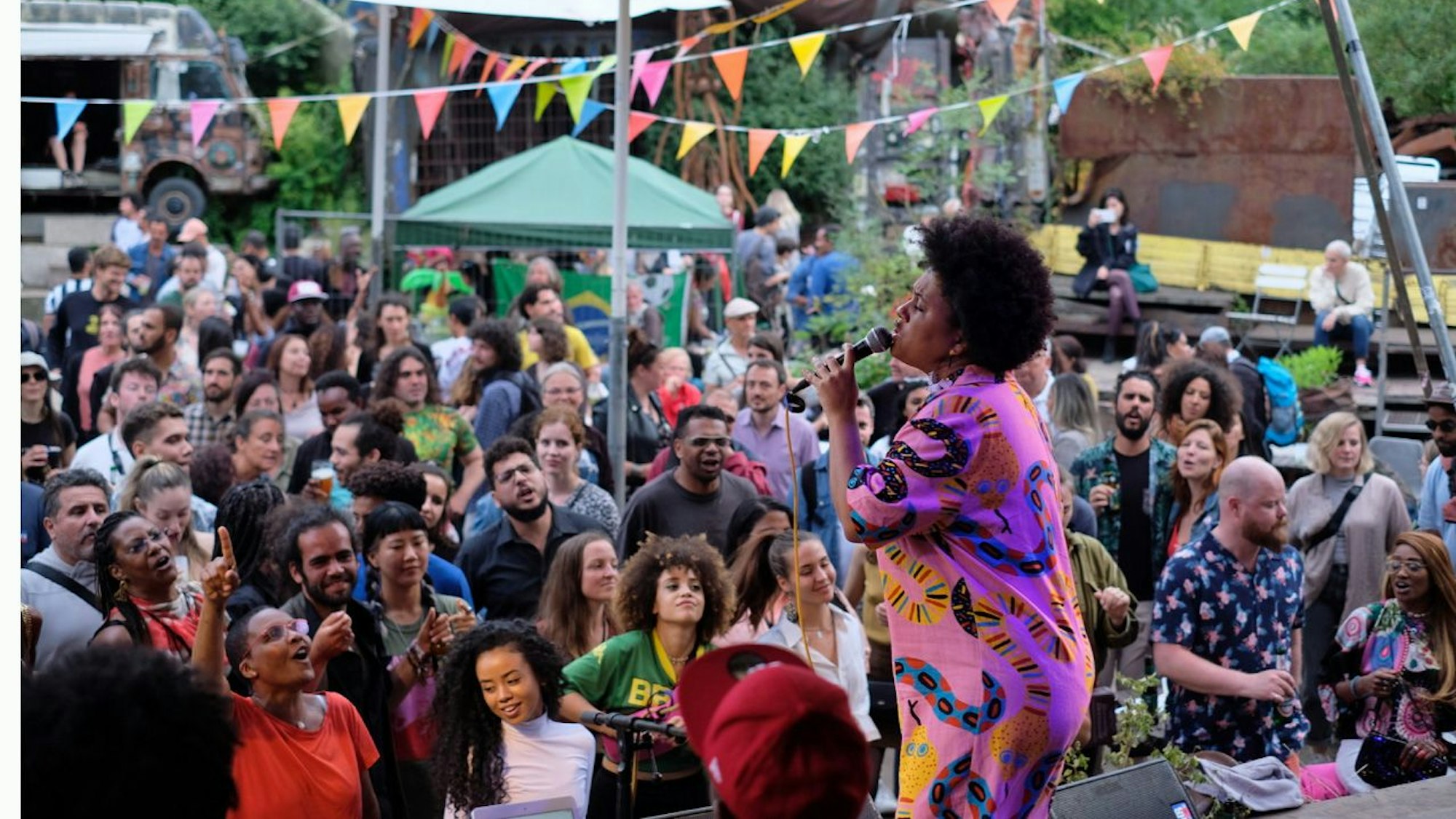 Menschen stehen vor einer Bühne im Odonien, wo eine Sängerin beim Festival Brasilonia auftritt.