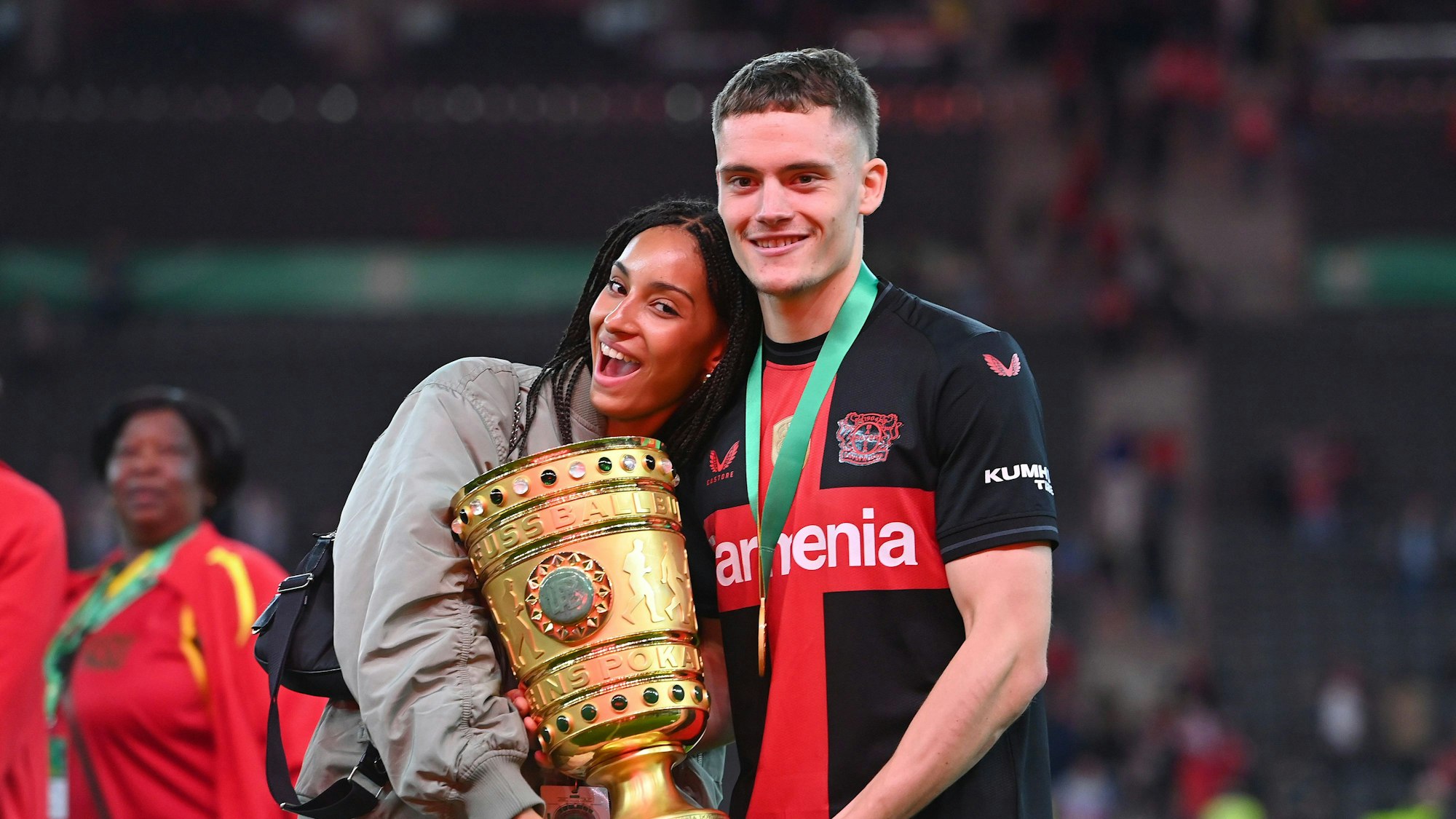 Florian Wirtz und seine Freundin Aaliyah halten den Bundesliga-Pokal.