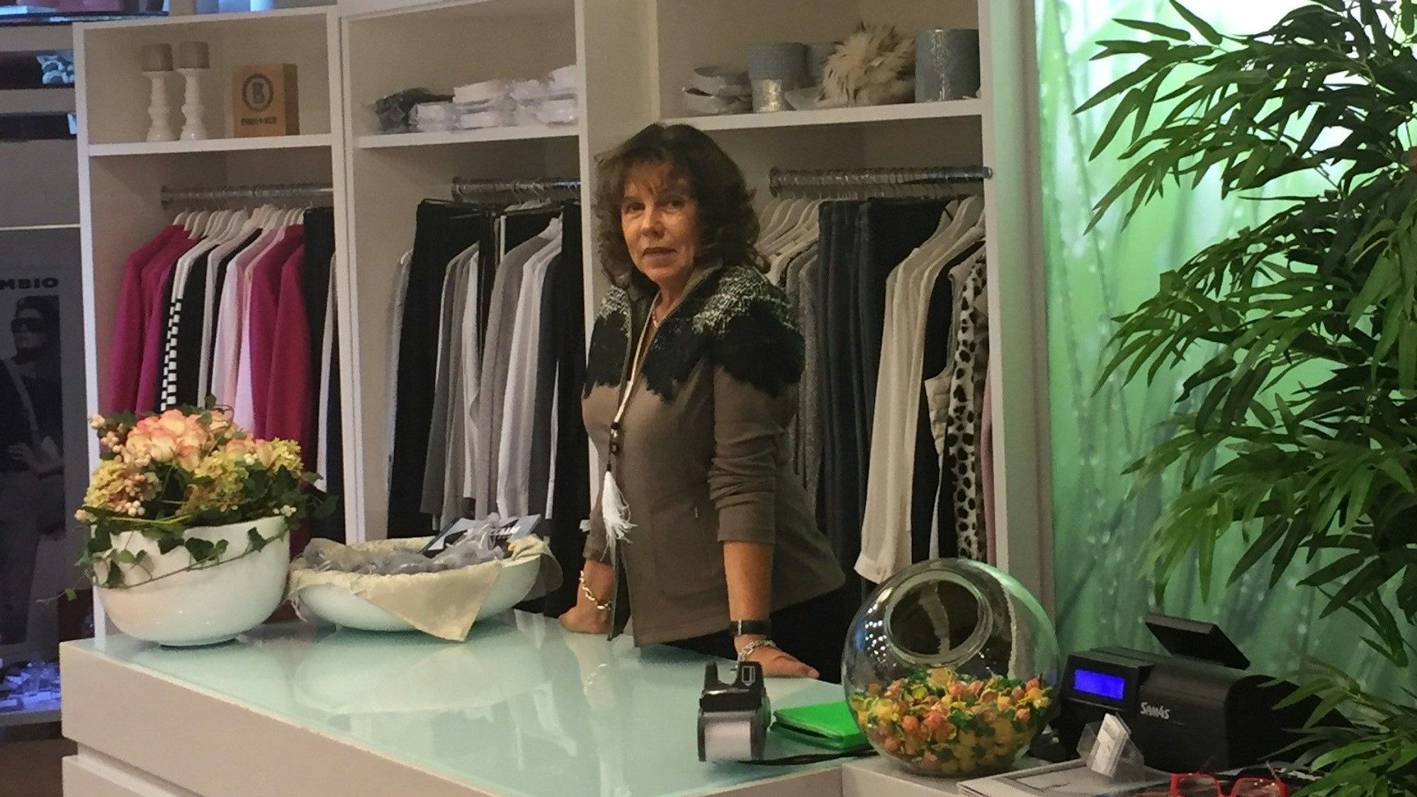 Eine Frau hinter der Verkaufstheke ihres Modegeschäfts