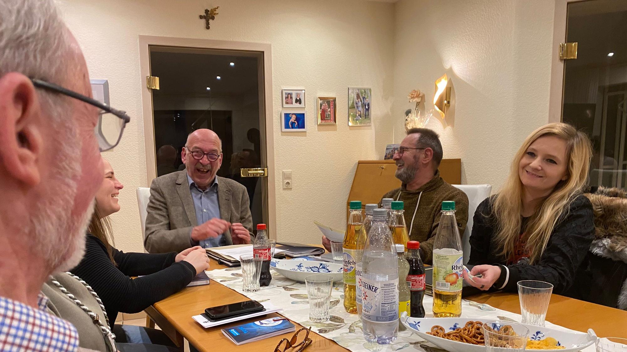 Das Team sitzt rund um einen Tisch, auf dem Getränke und Knabbereien.