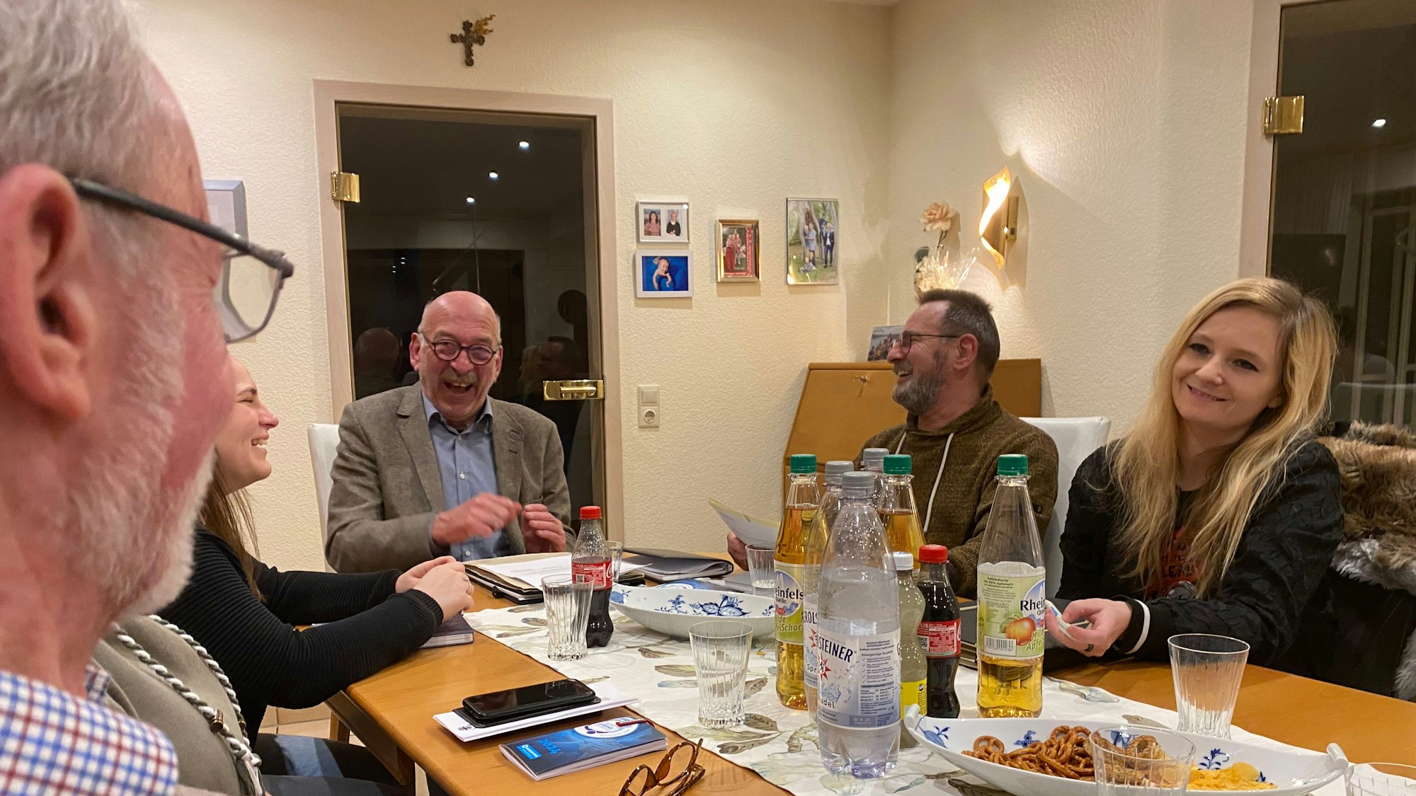 Das Team sitzt rund um einen Tisch, auf dem Getränke und Knabbereien.